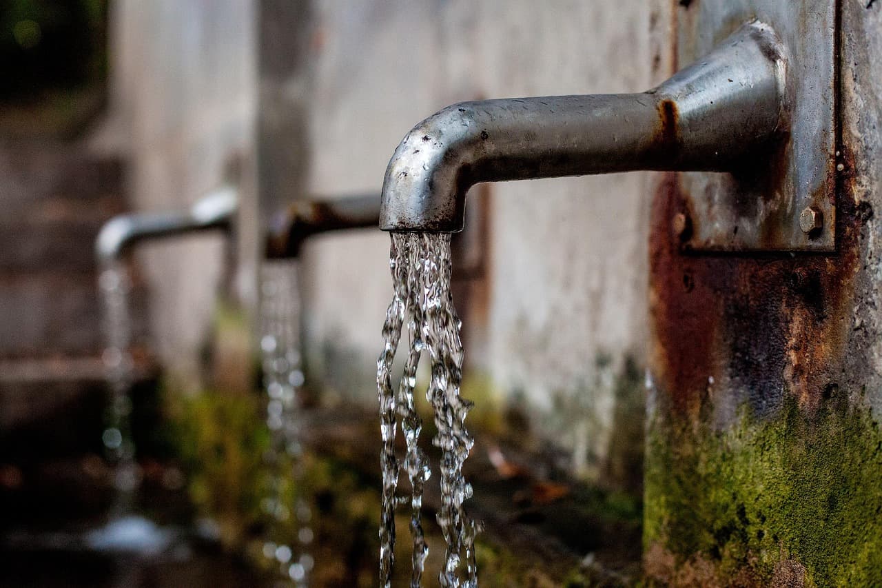 Familie trinkt gemeinsam Wasser aus dem Hahn